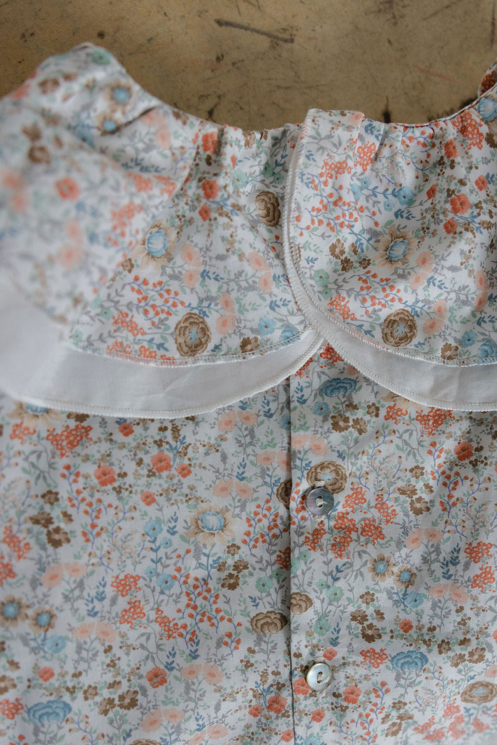 Floral patterned shirt with a collar on a wooden surface