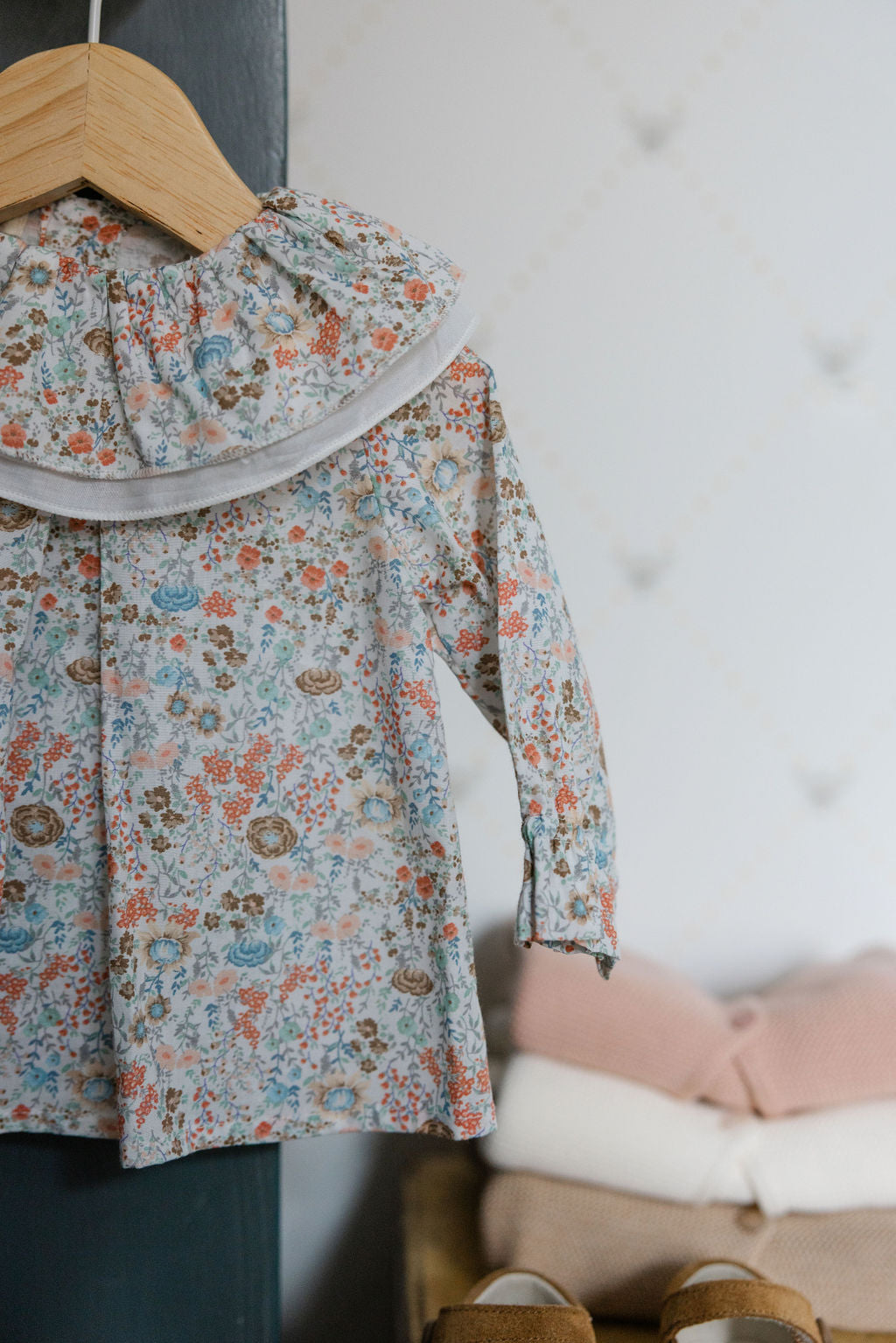 Floral blouse on a hanger against a neutral background