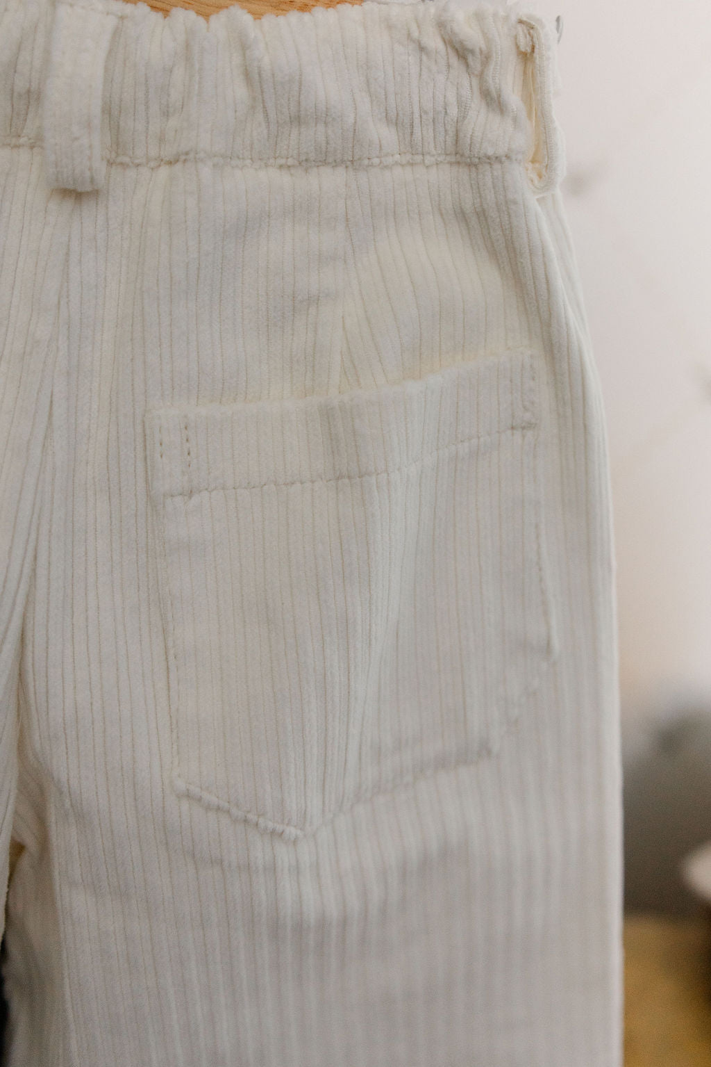 Light blue striped pants with a pocket detail on a plain background