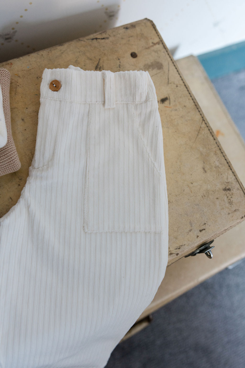 White ribbed garment with a button on a wooden surface
