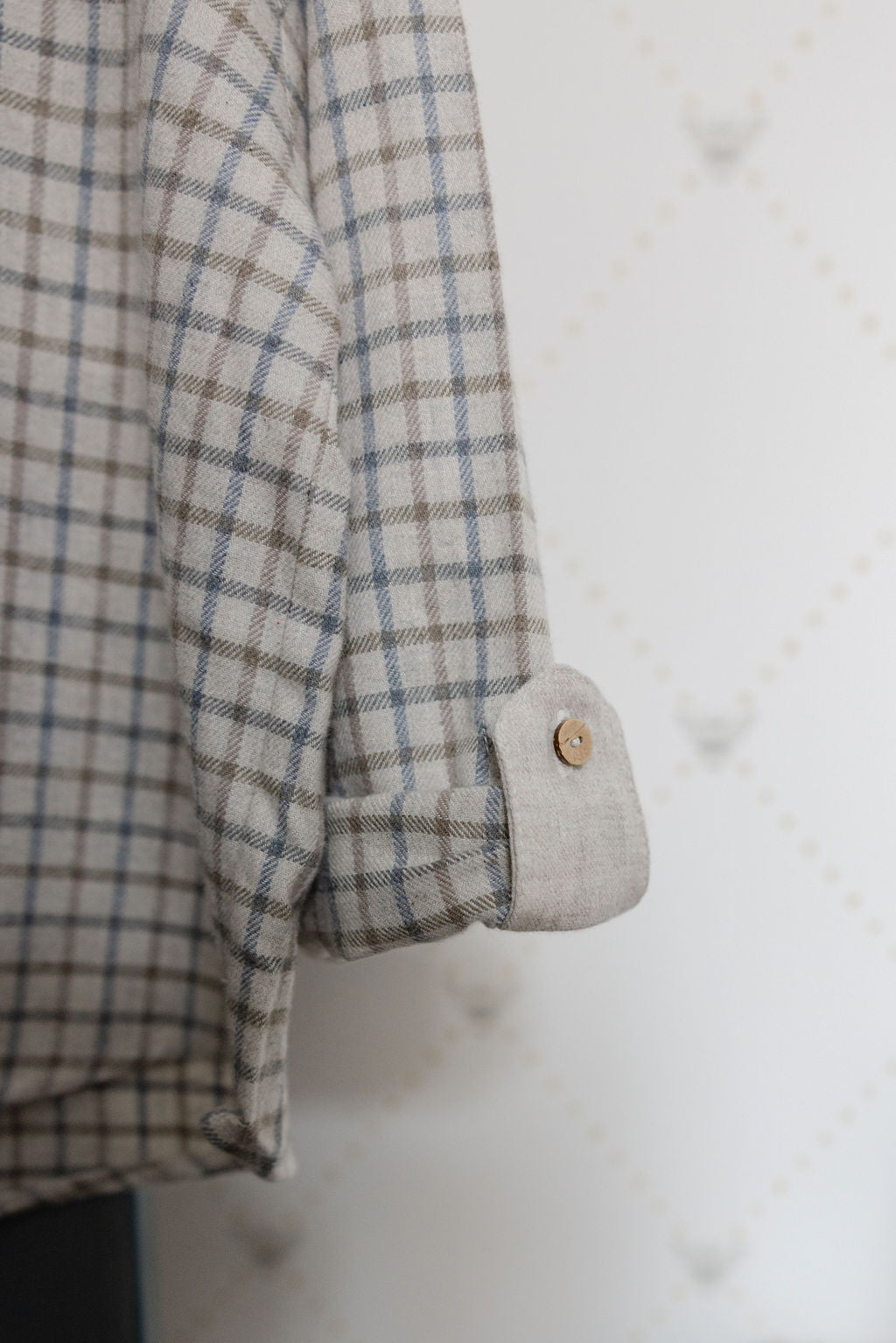 Close-up of a plaid shirt with a button on a textured white background