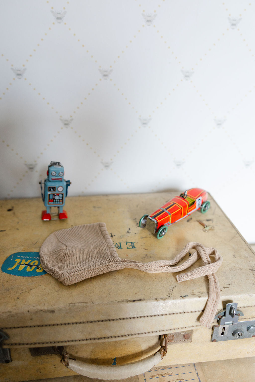 Vintage suitcase with a robot, car, and beige bonnet with textured white backgrounding