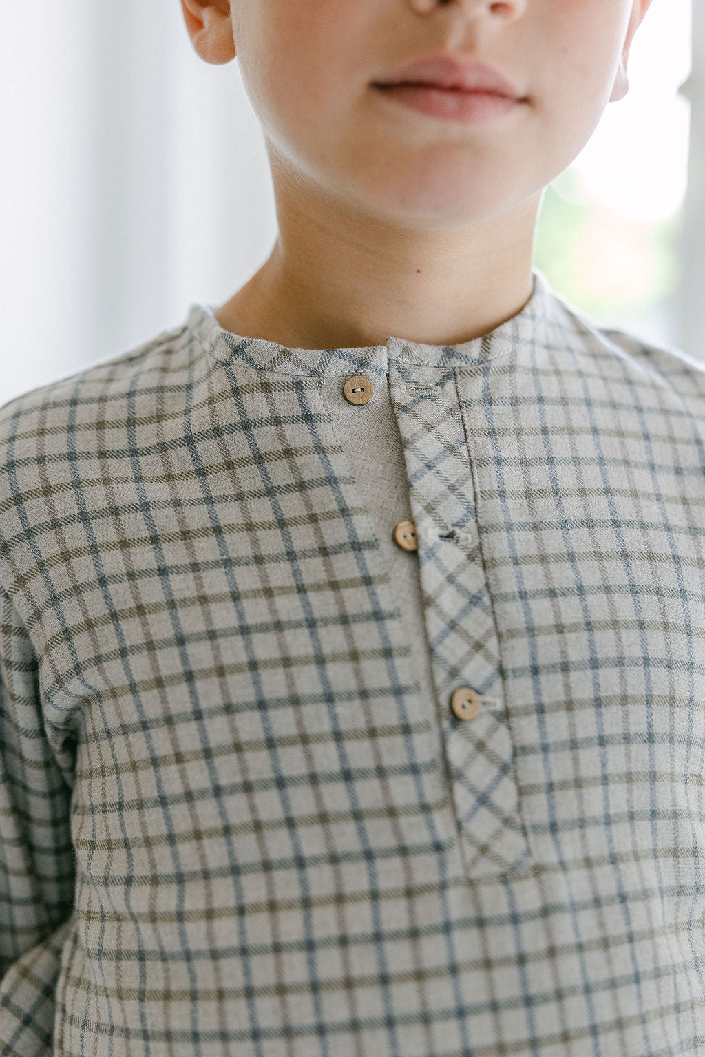 Person wearing a checkered shirt with a blurred background
