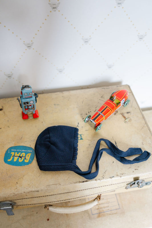 Vintage suitcase with a blue bonnet, orange toy car, and robot on a light background